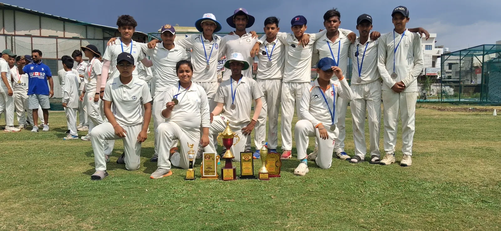 Cricketers in whites gathered for a team photograph with trophies