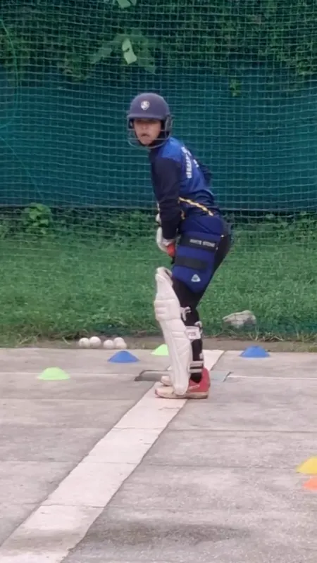 A helmeted batter practising a stroke in the academy nets