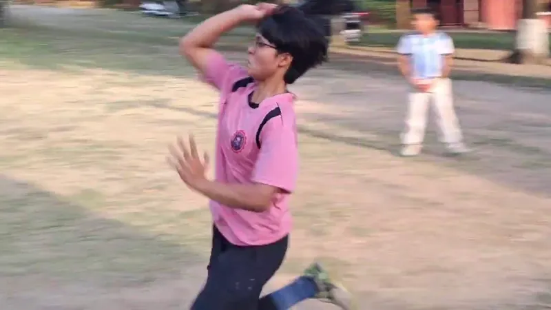 A young bowler running in and completing a delivery beside the nets