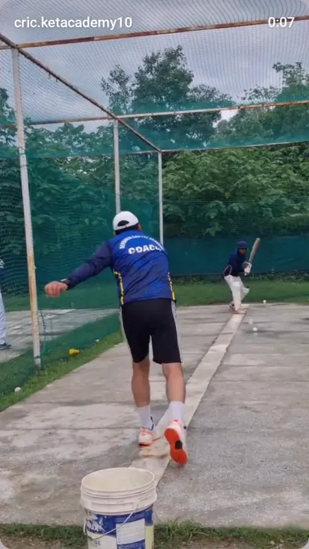 A coach feeding deliveries to a batter in the academy nets
