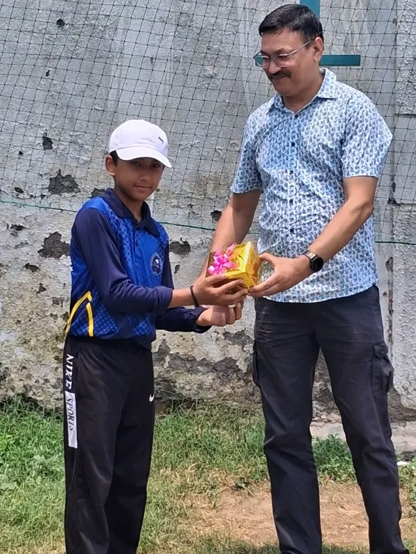 A young cricketer receiving a trophy at the ground