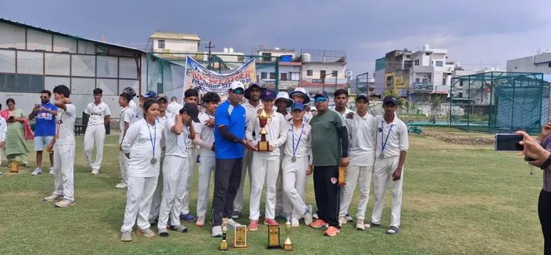 Players and adults gathered on the cricket ground with trophies